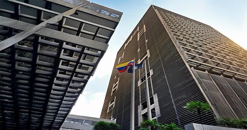 Fachada de la sede del Banco Central de Venezuela en Caracas, vista desde abajo, con la bandera de Venezuela en el asta.