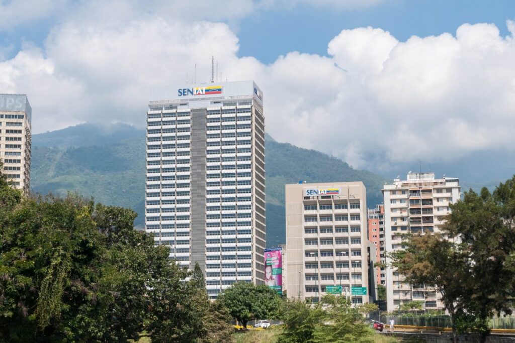 Torre de la sede del Seniat en Caracas, con el logo del Seniat en lo alto y el cerro El Ávila al fondo.